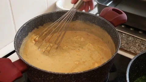 Mixing sauce with meat pieces. Using whisk for salmon sauce for lasagna Stock Footage 232005907