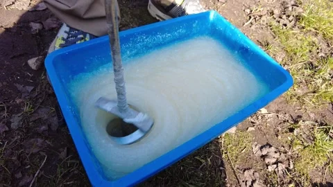 Mixing simple ingredients to create a paste in a blue container outdoors near gr Stock Footage 332064788