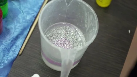 Mixing soap base with the sparkles and tastes in the glass Stock Footage 74361034
