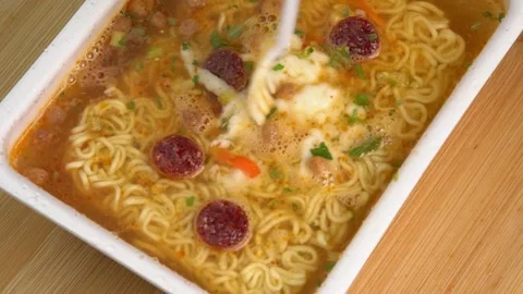 Mixing spices in done Instant noodles in a bowl rotate on wooden background, Stock-Footage 244815212