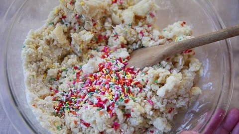 Mixing sprinkles into batter from overhead Stock Footage 102734628