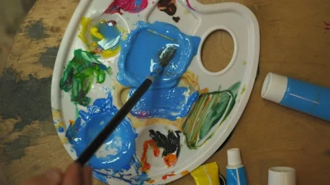 Mixing taking blue paint on a plastic paint palette brush Stock Footage 155029886