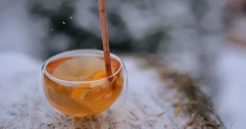 Mixing tea with lemon slices using wooden stick outdoors winter time Stock Footage 263017947