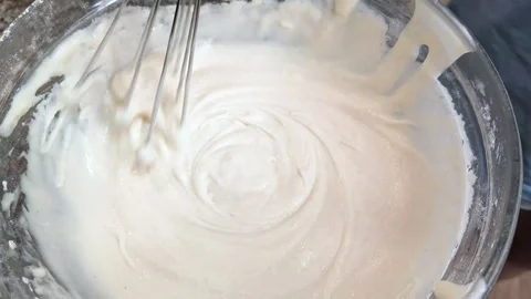 Mixing thick, white, creamy batter with a metal whisk in a bowl during the Video stock 342617778