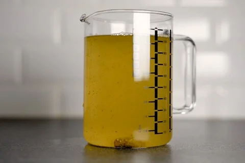 Mixing a vegetable bouillon stock cube in boiling water in a glass measuring jar Stock Footage 109014551