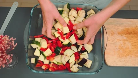 Mixing vegetables in a transparent baking dish with your hands Stock Footage 249079847