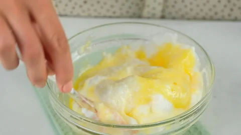 Mixing whipped foamy white eggs with yolk in bowl cooking omelet on kitchen. Video stock 313128941