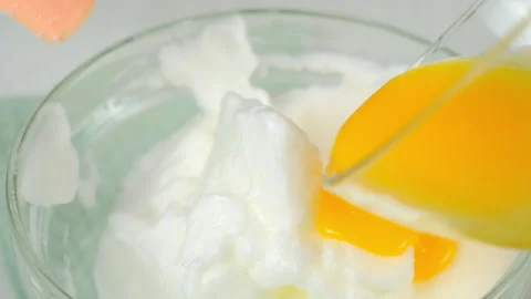 Mixing whipped foamy white eggs with yolk in bowl cooking omelet on kitchen. Video stock 313128978