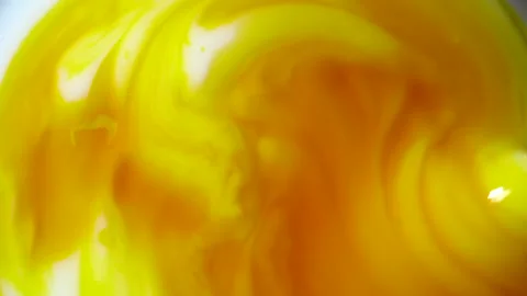 Mixing white milk with orange beta carotene in rotation Closeup Stock Footage 152306280