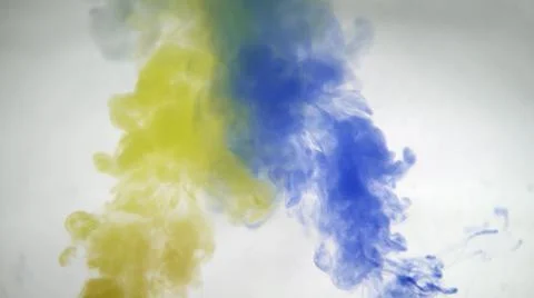 Mixing yellow and blue paint colors in water. Colored smoke effect Stock Photos