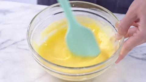 Mixing yolk into cake batter until smooth and blend well in a glass bowl Stock Footage 117271792
