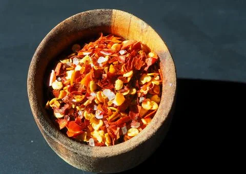 A mixture of cayenne pepper, red pepper and sea salt in a wooden bowl isolate 库存照片