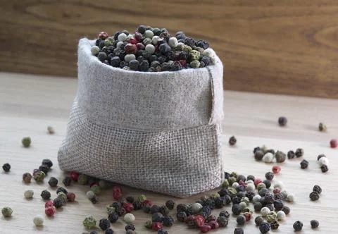 Mixture colored peppers in a canvas sack on wooden kitchen table. Stock Photos