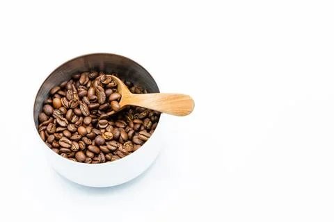Mixture of different kinds of roasted coffee beans with wooden spoon in white Foto stock