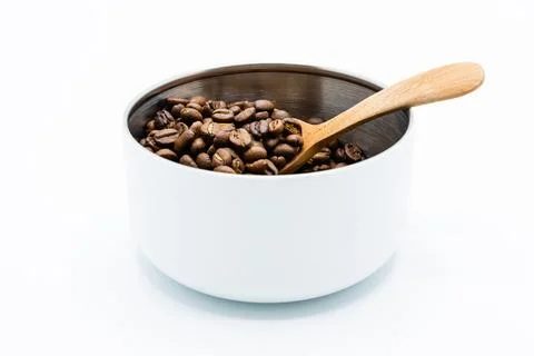 Mixture of different kinds of roasted coffee beans with wooden spoon in white Foto stock