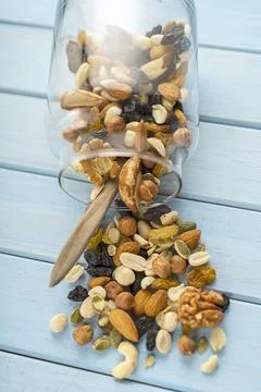 A mixture of loose nuts. Storage of nuts in a glass jar, on a wooden table. C Stock Photos