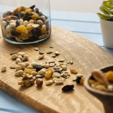 A mixture of loose nuts. Storage of nuts in a glass jar, on a wooden table. S Stock Photos