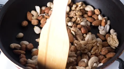 The mixture of nuts is fried in a frying pan, stir with a wooden spatula. Concep Video stock 259462981