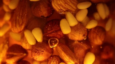 A mixture of nuts moves in honey Stock Footage 129273467