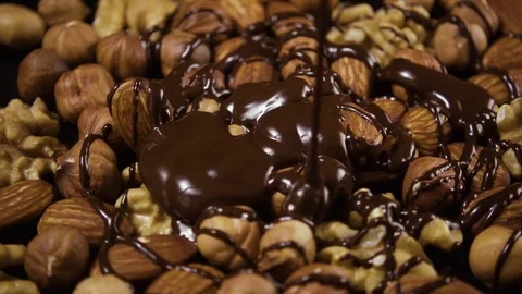 A mixture of nuts is poured abundantly with chocolate. High speed Stock Footage 74733018