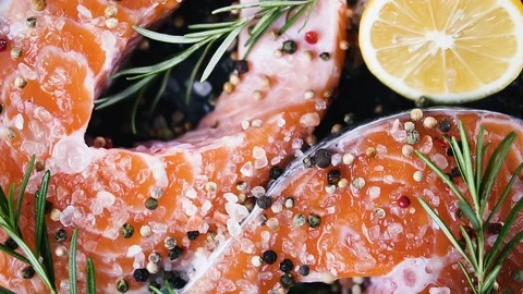 Mixture of peppers drops on raw salmon steaks. Video stock 125191764