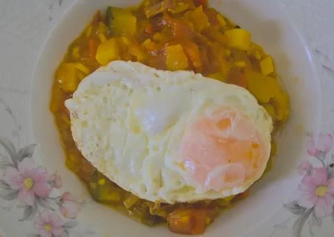 Mixture of various roasted vegetables and a fried egg on top Stock Photos