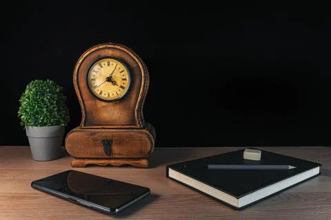 Mobile and notebook with clock and plant on black background Foto stock