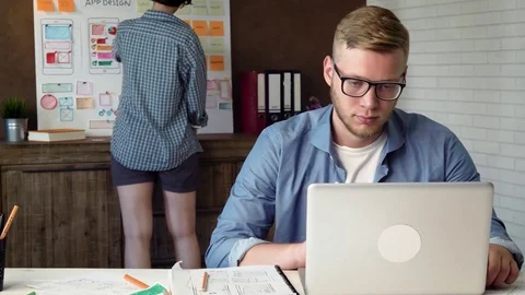 Mobile app developer working on new mobile application prototype on his laptop Stock Footage