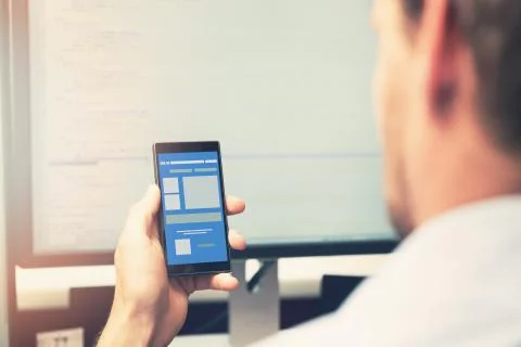 Mobile app development - smart phone with application wireframe in programmer Stock Photos