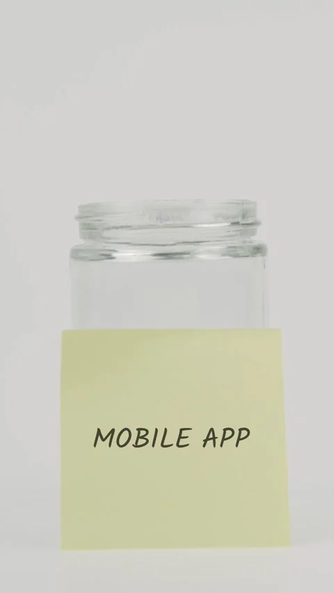 Mobile app text or word on yellow sticky note attached to glass jar Stock Footage 311755772