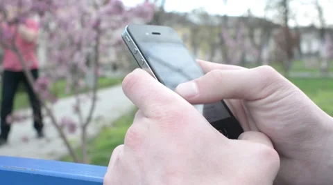 Mobile Cell Phone in Hands of a Man - chatting wrighting sms - in a city park Stock Footage 62294391