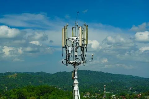 Mobile communication tower against the background of clouds and green hills Stock Photos