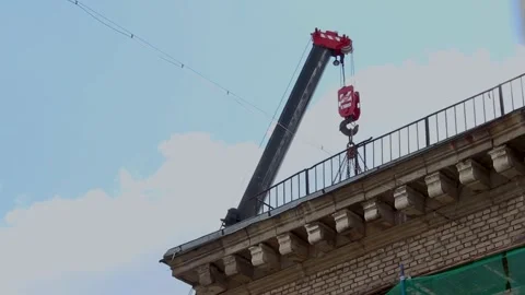 Mobile crane boom extending over old brick building rooftop during renovation 库存影片 341833931