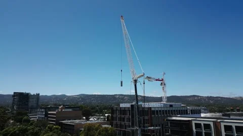 A mobile crane hoists a heavy load while dismantling a tower crane atop a Stock Footage 303062324