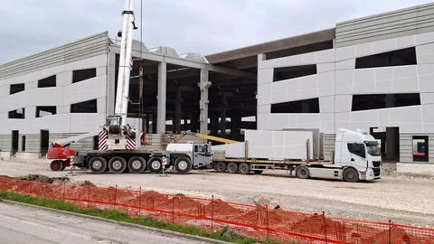 Mobile crane installing precast concrete wall panels from a truck. Stock Photos