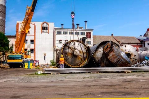 Mobile crane lay down big old metal tank Worker is helping to keep balance an Stock Photos