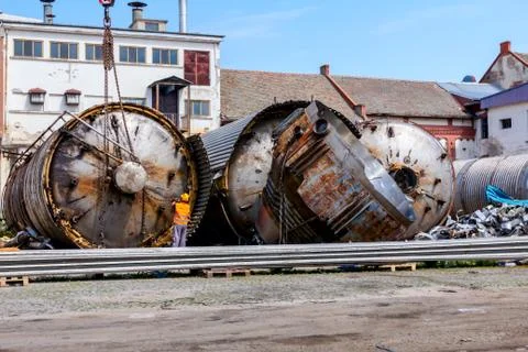Mobile crane lay down big old metal tank Worker is helping to keep balance an Stock Photos