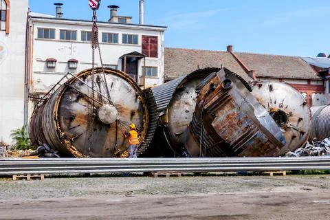 Mobile crane lay down big old metal tank Worker is helping to keep balance Stock Photos