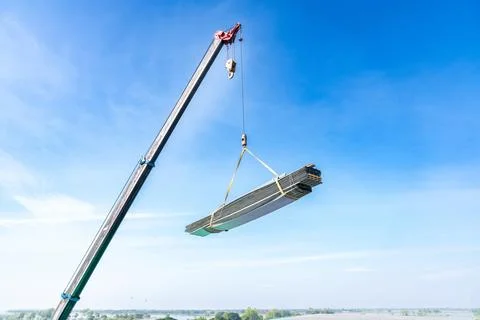 Mobile crane lifting a large bundle of metal or steel roofing sheets agains.. Foto stock