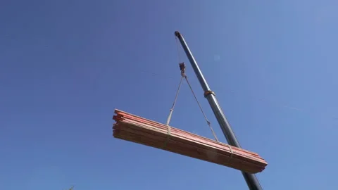 Mobile crane lifting stack of a long, thin, flat piece of boards, crane hook Stock Footage 138087650