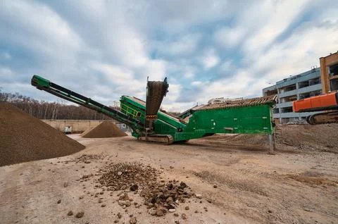 Mobile crushing and sorting complex works among soil piles Stock Photos
