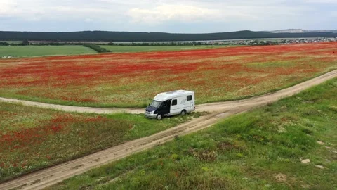 The mobile home is located in a field of red poppies. Camper. Motorhome Vidéo 157447724