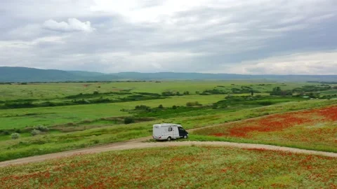The mobile home is located in a field of red poppies. Camper. Motorhome Vidéo 157576820