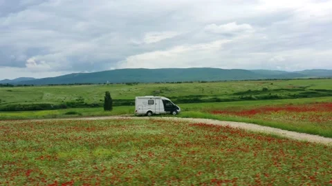 The mobile home is located in a field of red poppies. Camper. Motorhome Vidéo 158138029