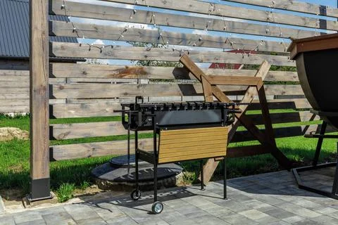 Mobile Metal Grill on Backyard Patio Against Wooden Fence Foto stock