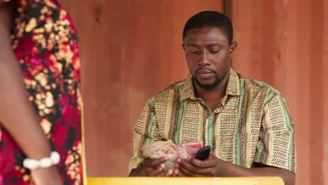 Mobile Money Agent Makes Cash Withdrawal for Customer at Outdoor Stand 库存影片 346240599