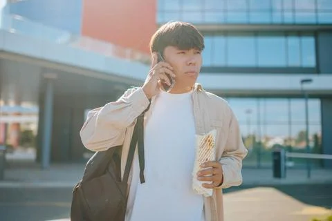 Mobile Munchies Young Asian Korean Student Multitasks with Phone and Fast Food Stock Photos
