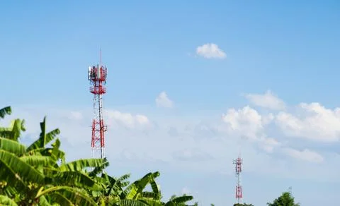 Mobile network Cellular communication tower over forested against the blue sk Stock Photos