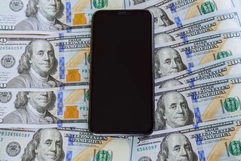 Mobile phone on a background of dollars. Deciding the exchange rate. Stock Photos