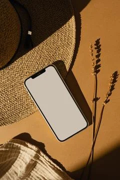 Mobile phone with blank copy space screen. Straw hat, muslin cloth, dried gra Stock Photos